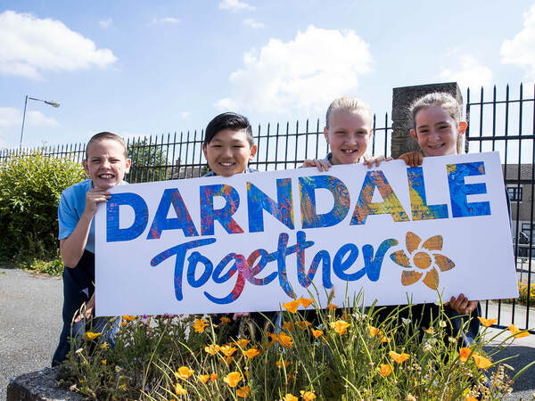 children hold sign together in darndale
