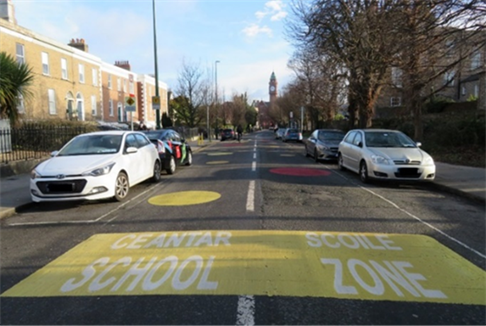 Title: Photo of an existing school zone, yellow, painted road surface sign on Leinster Road, Rathmines, Dublin 6.