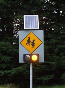 Title: Photo of a school ahead sign with flashing amber signal.